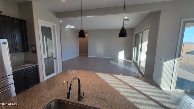 kitchen with stainless steel refrigerator, hanging light fixtures, and sink