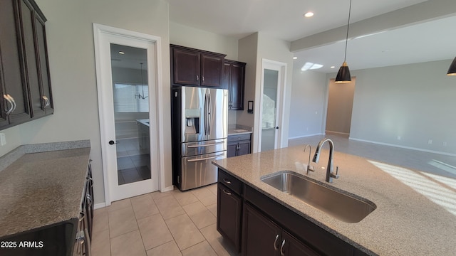 kitchen with sink, light stone countertops, light tile patterned floors, decorative light fixtures, and stainless steel fridge with ice dispenser