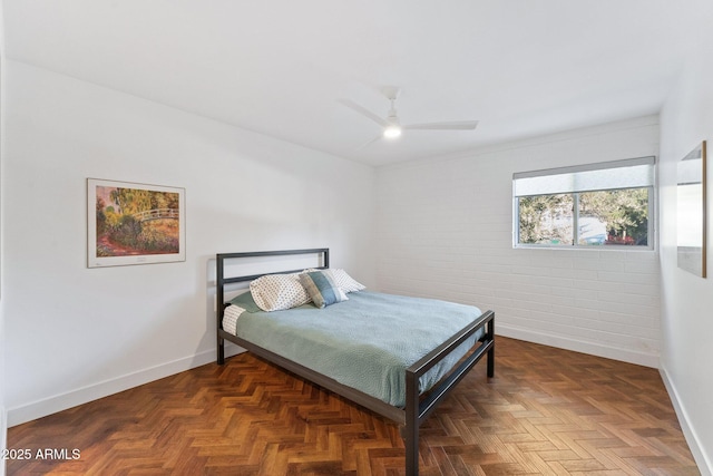 bedroom with dark parquet flooring, ceiling fan, and brick wall