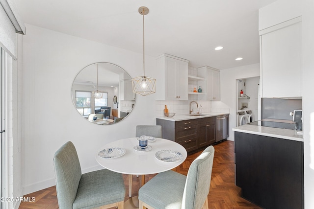 dining space with sink, dark parquet floors, and washer and clothes dryer