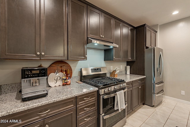 kitchen featuring dark brown cabinets, light stone countertops, light tile patterned floors, and stainless steel appliances