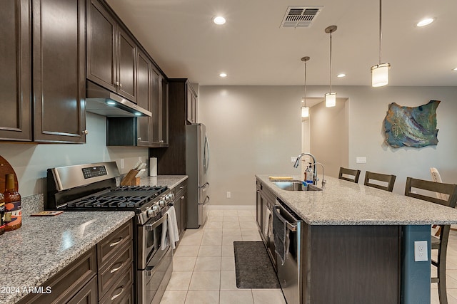 kitchen with sink, a kitchen bar, stainless steel appliances, and a center island with sink