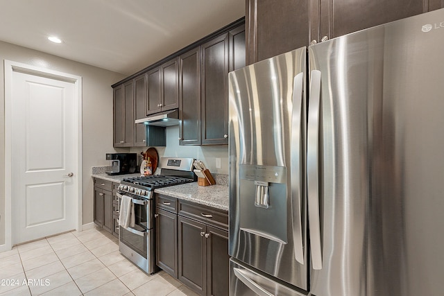 kitchen featuring light tile patterned floors, dark brown cabinetry, stainless steel appliances, and light stone counters