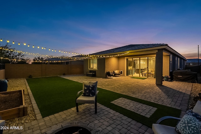 back house at dusk featuring a patio