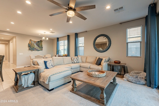 tiled living room with ceiling fan with notable chandelier