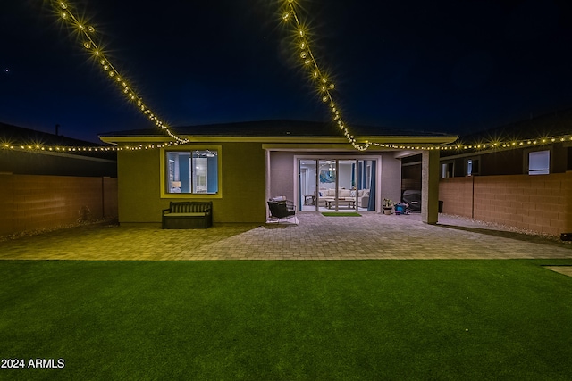 back house at twilight with a lawn and a patio area