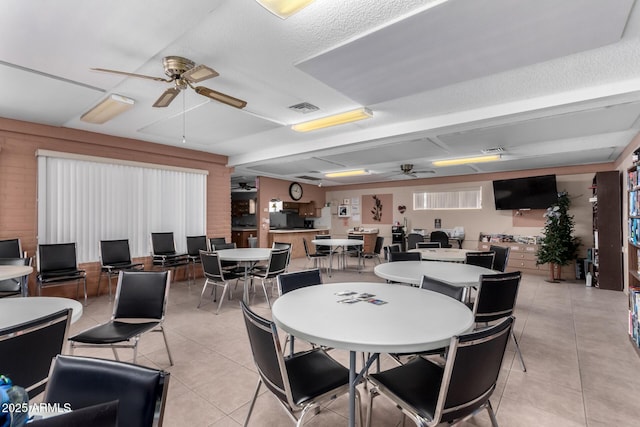 tiled dining space with a textured ceiling, ceiling fan, and wood walls