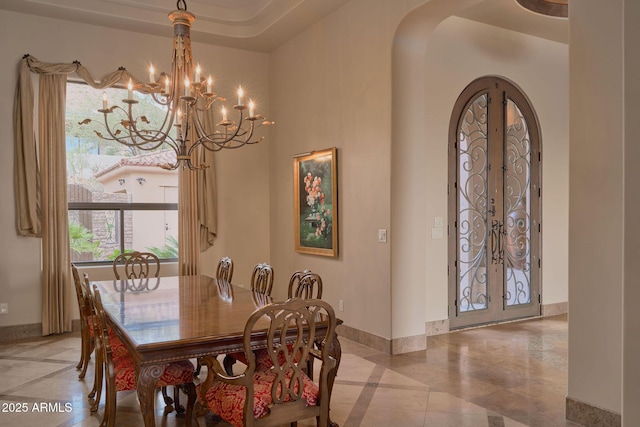 dining area with french doors, baseboards, arched walkways, and a notable chandelier