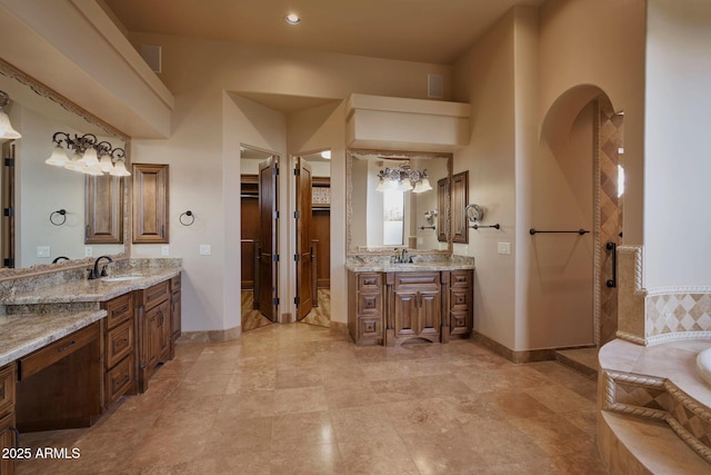 bathroom featuring baseboards, two vanities, and a sink