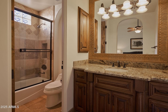 bathroom featuring toilet, bath / shower combo with glass door, vanity, and ceiling fan