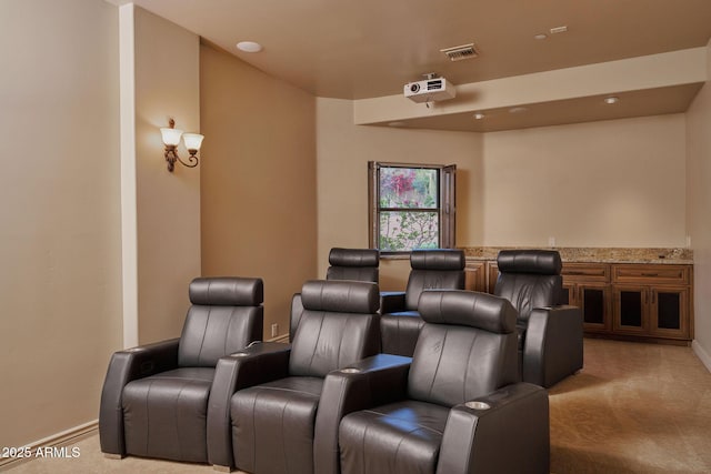 cinema room featuring light colored carpet, visible vents, and baseboards