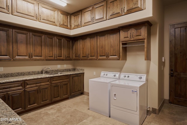 washroom featuring cabinet space, washing machine and dryer, baseboards, and a sink