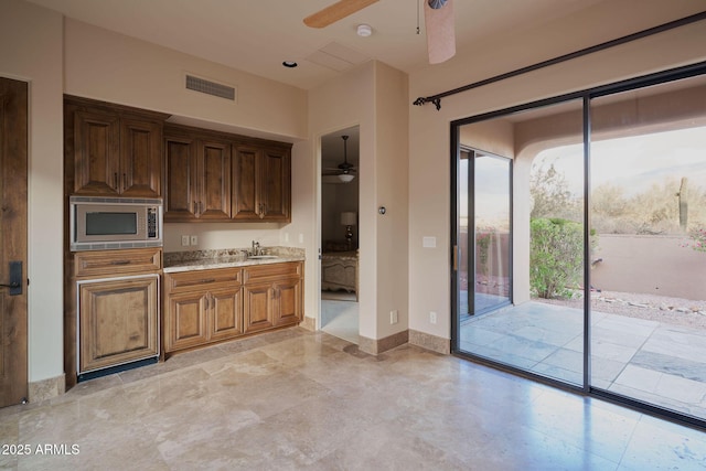kitchen with stainless steel microwave, ceiling fan, baseboards, and visible vents