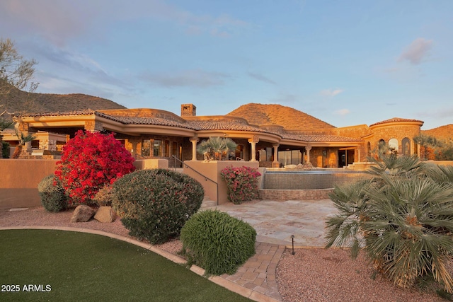 back of property featuring stucco siding, fence, a tiled roof, and a chimney