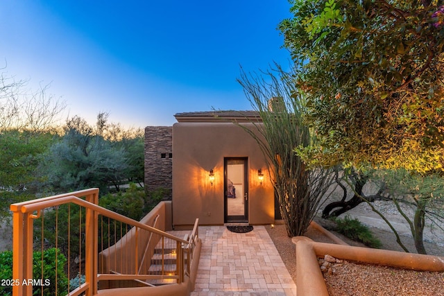 10267 E Cinder Cone Trl, Scottsdale, AZ 85262 - exterior entry at dusk with a balcony, stucco siding, and a chimney