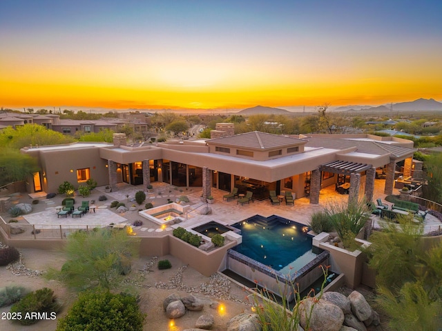 10267 E Cinder Cone Trl, Scottsdale, AZ 85262 - back of property at dusk with a fenced backyard, an in-ground hot tub, a patio area, an outdoor pool, and stucco siding