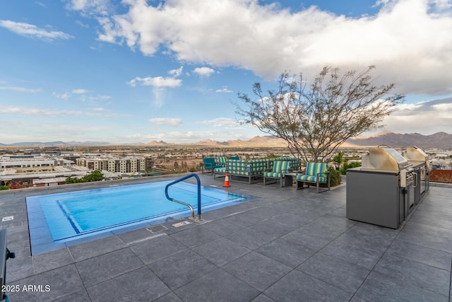 pool featuring a mountain view, a patio, a grill, and an outdoor kitchen