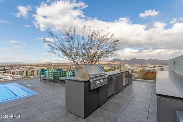 view of patio / terrace with exterior kitchen, a mountain view, and a grill