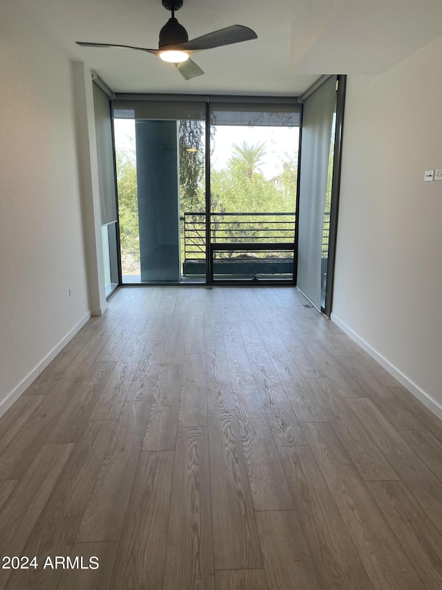 empty room featuring expansive windows, a healthy amount of sunlight, and wood finished floors