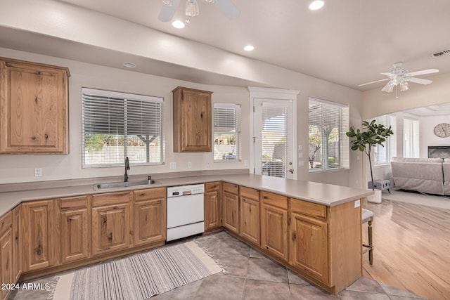 kitchen with white dishwasher, sink, light hardwood / wood-style floors, kitchen peninsula, and ceiling fan