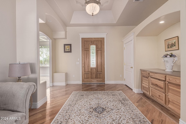 foyer entrance featuring light hardwood / wood-style flooring and a raised ceiling