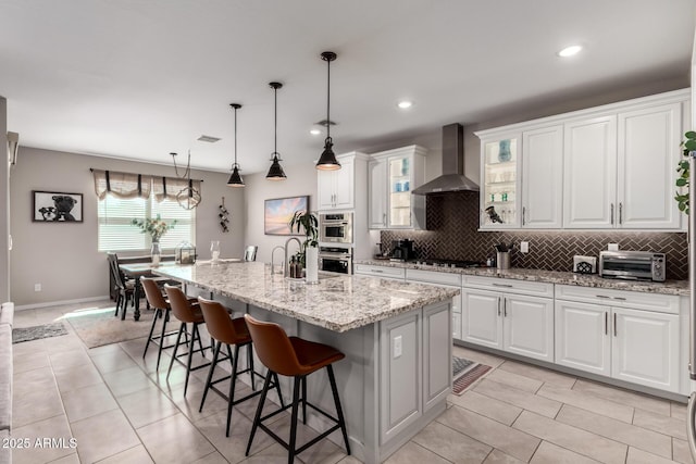 2229 N 139th Dr, Goodyear, AZ 85395 - kitchen featuring wall chimney range hood, gas cooktop, a kitchen breakfast bar, backsplash, and a toaster