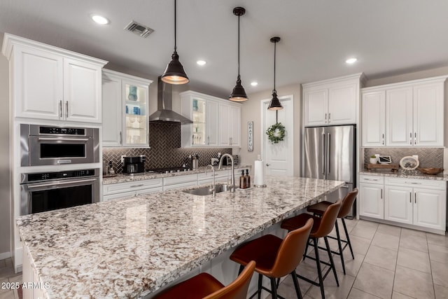 2229 N 139th Dr, Goodyear, AZ 85395 - kitchen with visible vents, decorative backsplash, recessed lighting, wall chimney exhaust hood, and stainless steel appliances