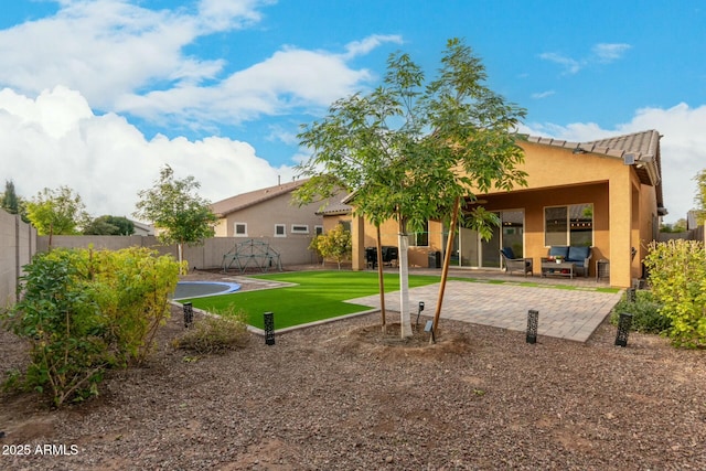 rear view of house with a patio area, a trampoline, and a lawn