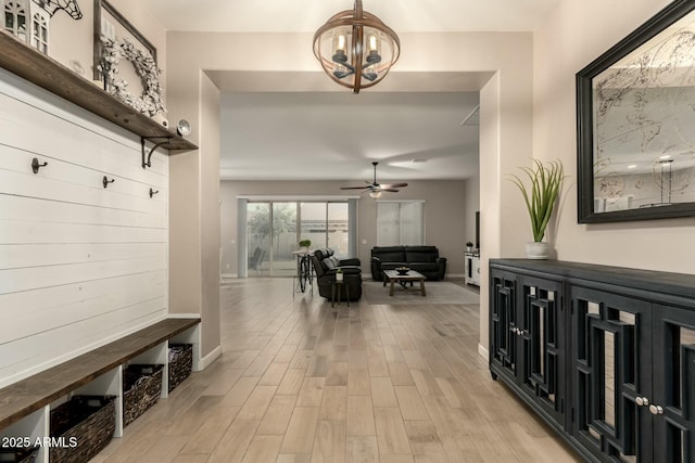 mudroom with ceiling fan with notable chandelier and light hardwood / wood-style flooring