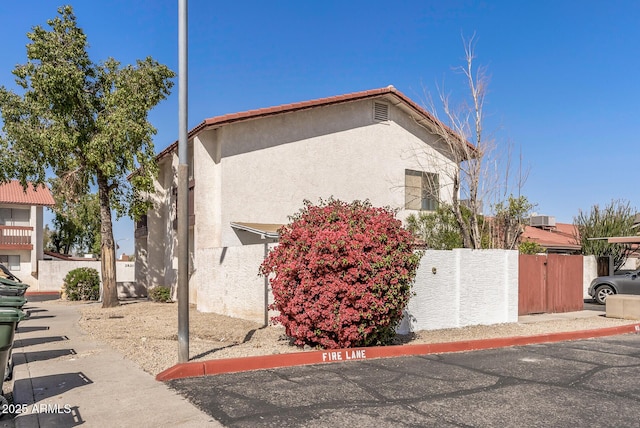 view of side of home with stucco siding and fence