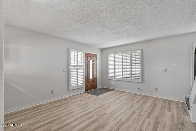 entryway with baseboards, light wood-style floors, and a textured ceiling