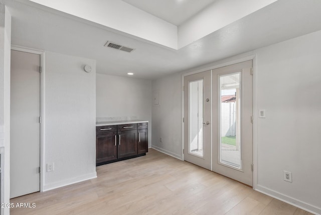 entryway with light wood-style floors, french doors, visible vents, and baseboards