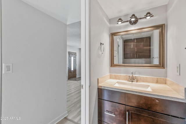 bathroom with baseboards, wood finished floors, and vanity