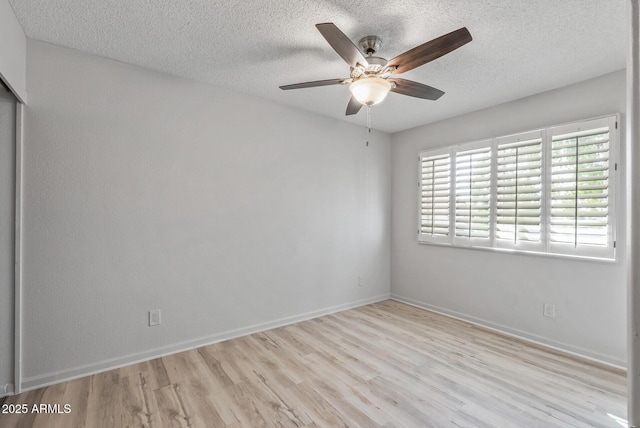 spare room featuring ceiling fan, a textured ceiling, baseboards, and wood finished floors