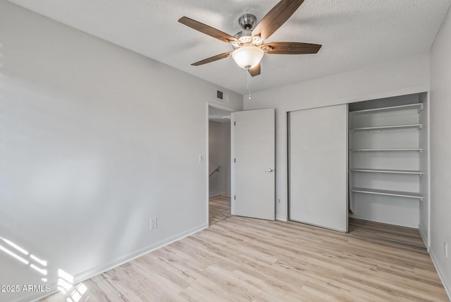 unfurnished bedroom with a ceiling fan, visible vents, a closet, a textured ceiling, and light wood-type flooring