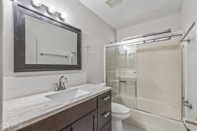 full bathroom with vanity, toilet, visible vents, and combined bath / shower with glass door