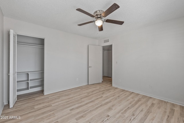 unfurnished bedroom featuring a closet, a textured ceiling, visible vents, and wood finished floors