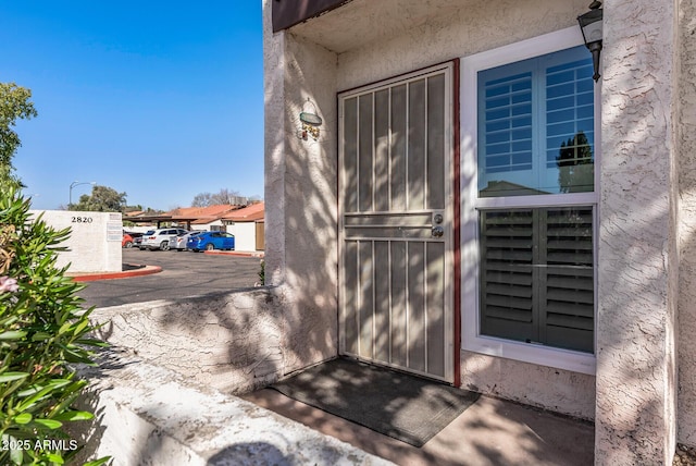 view of exterior entry featuring stucco siding and uncovered parking