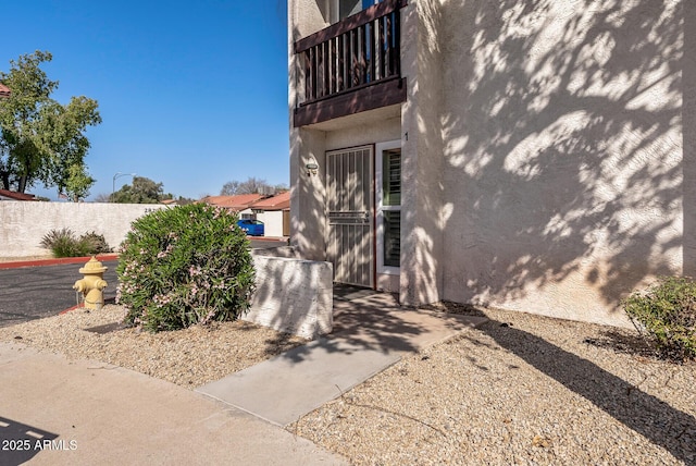 entrance to property with stucco siding and a balcony