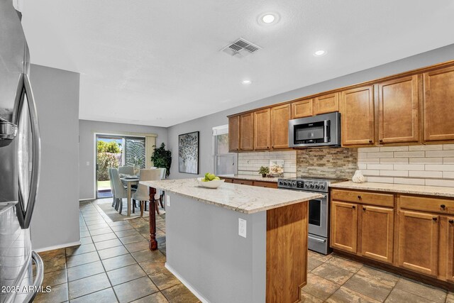 1314 S Bridgegate Dr, Gilbert, AZ 85296 - kitchen with stainless steel appliances, a kitchen island, backsplash, light stone countertops, and recessed lighting