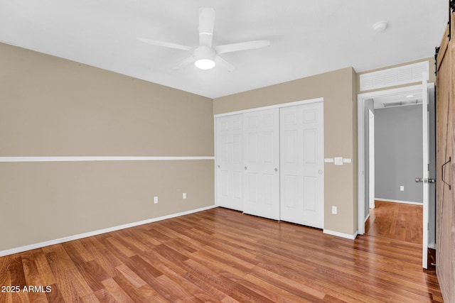 1314 S Bridgegate Dr, Gilbert, AZ 85296 - unfurnished bedroom featuring a barn door, light wood finished floors, baseboards, a closet, and ceiling fan
