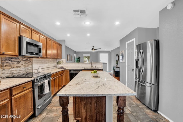 1314 S Bridgegate Dr, Gilbert, AZ 85296 - kitchen featuring stainless steel appliances, backsplash, a peninsula, a kitchen island, and a ceiling fan