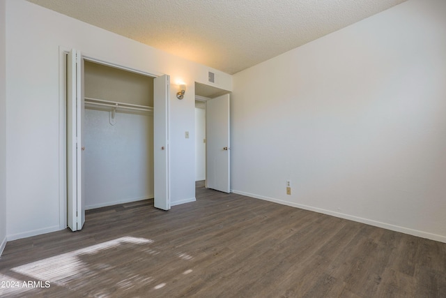 unfurnished bedroom featuring a textured ceiling, dark hardwood / wood-style flooring, and a closet