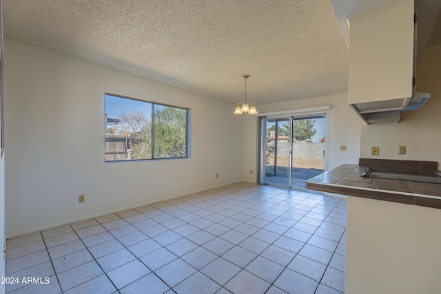 kitchen featuring a chandelier, pendant lighting, a textured ceiling, and tile counters