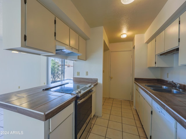 kitchen with dishwasher, electric stove, sink, light tile patterned floors, and a textured ceiling