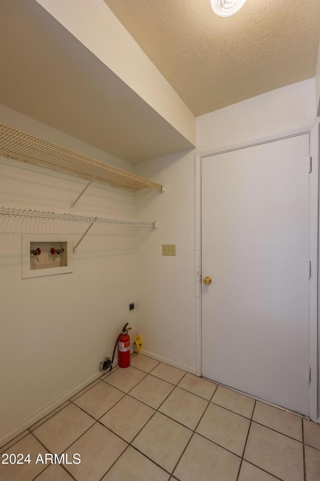 clothes washing area featuring washer hookup, electric dryer hookup, a textured ceiling, and tile patterned flooring