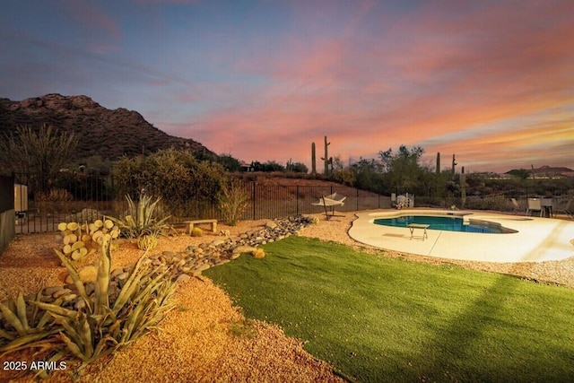 exterior space featuring fence, a mountain view, a patio, a lawn, and a pool