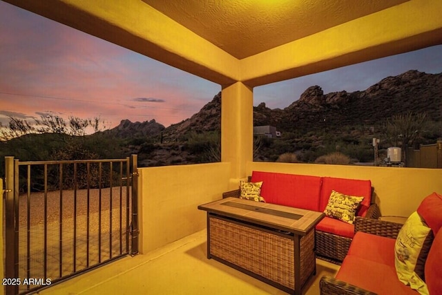 patio terrace at dusk featuring an outdoor hangout area, a mountain view, and a gate