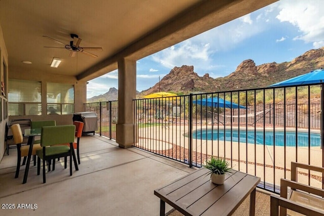 balcony with a mountain view, outdoor dining area, and a ceiling fan