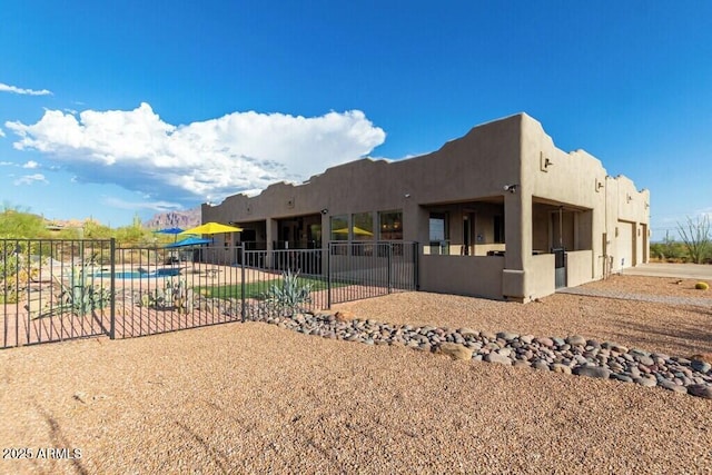 view of home's exterior featuring a patio, a garage, stucco siding, fence, and a fenced in pool